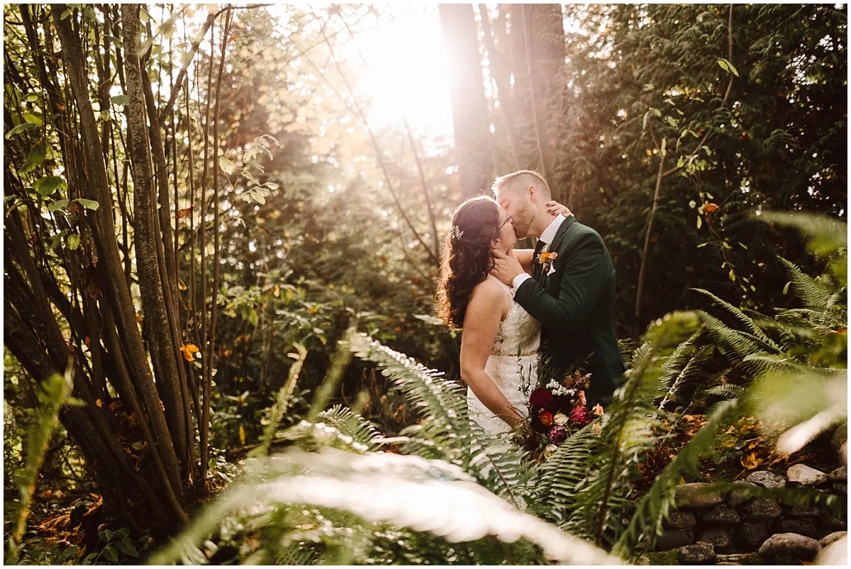 lodge at st edward grotto bride and groom kissing in the sunlight behind the ferns