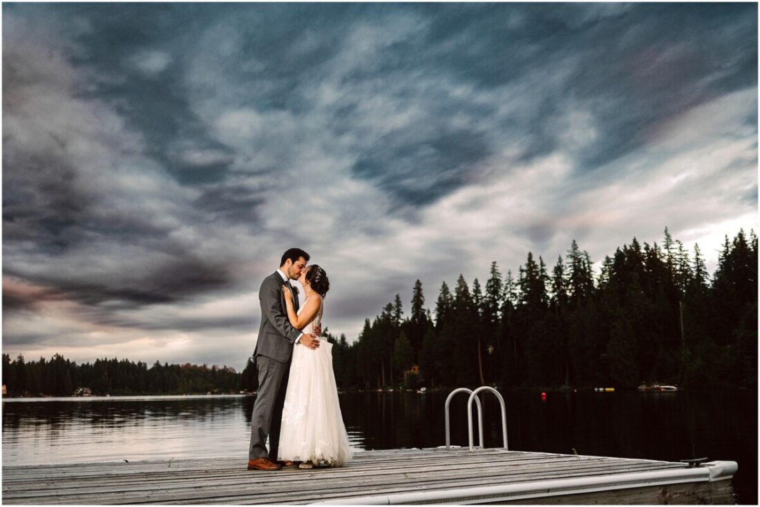 Green Gates at Flowing Lake wedding bride and groom on the dock during a stormy sunset kissing