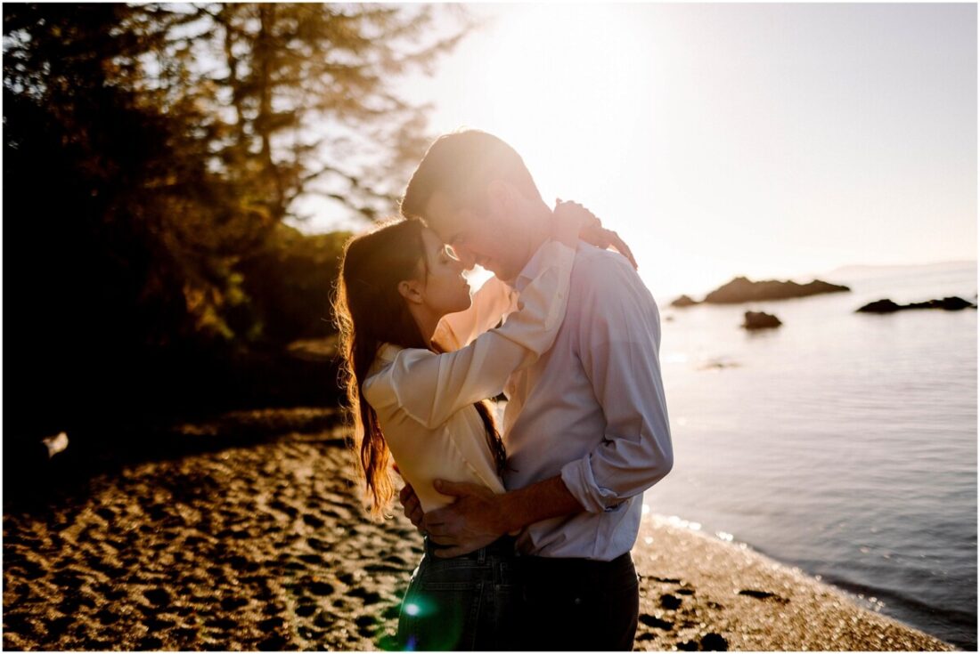 Rosario Beach Engagement session at sunset with bride and groom nose to nose and a warm sunflare behind them near oak harbor wa