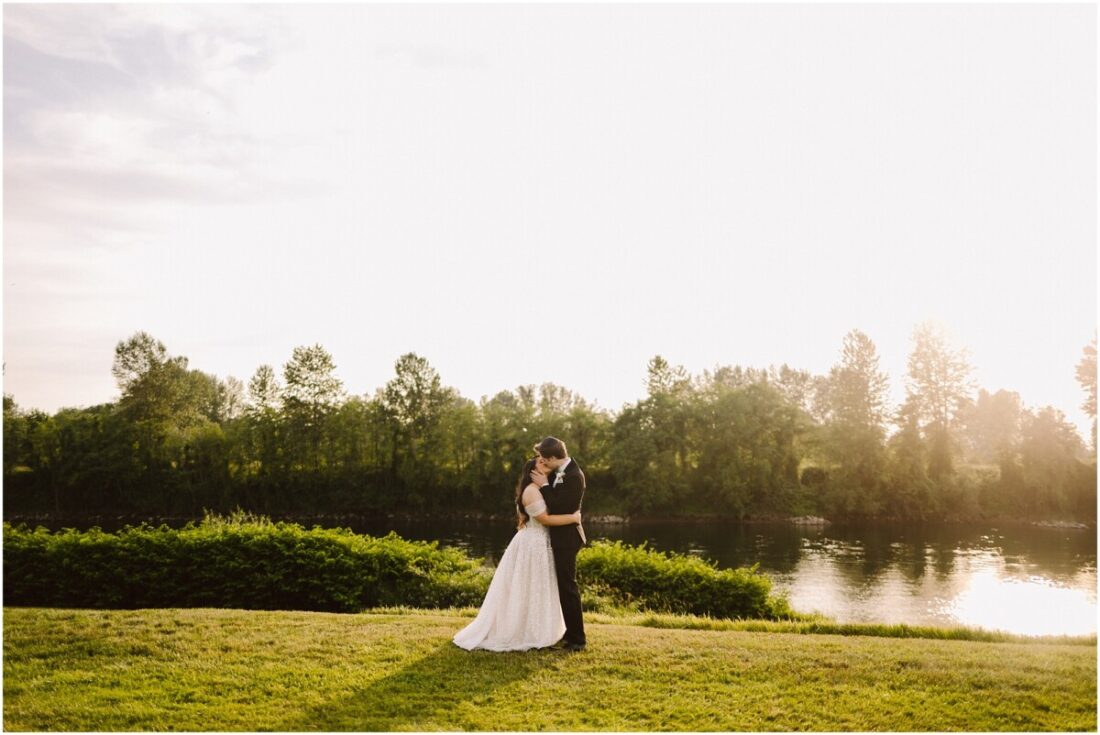 classic wedding at pemberton farm in snohomish bride and groom kissing on the grass with river in the background