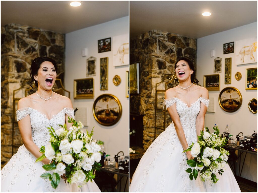 Snohomish Wedding Photographer GSquared Weddings A joyful bride in a white, off-the-shoulder wedding dress holds a bouquet of white flowers. She is laughing and standing in front of a stone wall adorned with various framed pictures. The setting appears to be indoors. Serving Seattle, Snohomish and Orlando