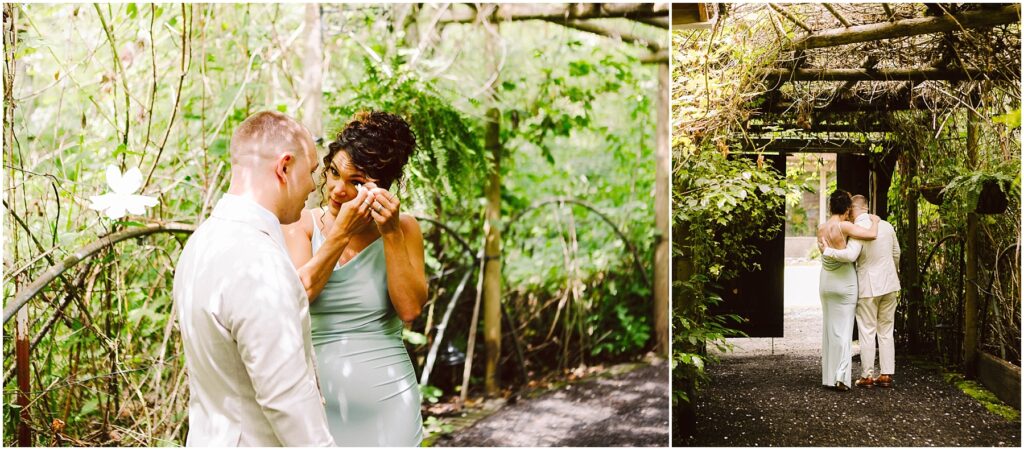 Snohomish Wedding Photographer GSquared Weddings A couple embraces and smiles in a lush garden setting, surrounded by greenery and wooden arches. The woman wipes her eye, appearing emotional. Both are dressed in white and light gray attire, creating an intimate, serene atmosphere. Serving Seattle, Snohomish and Orlando