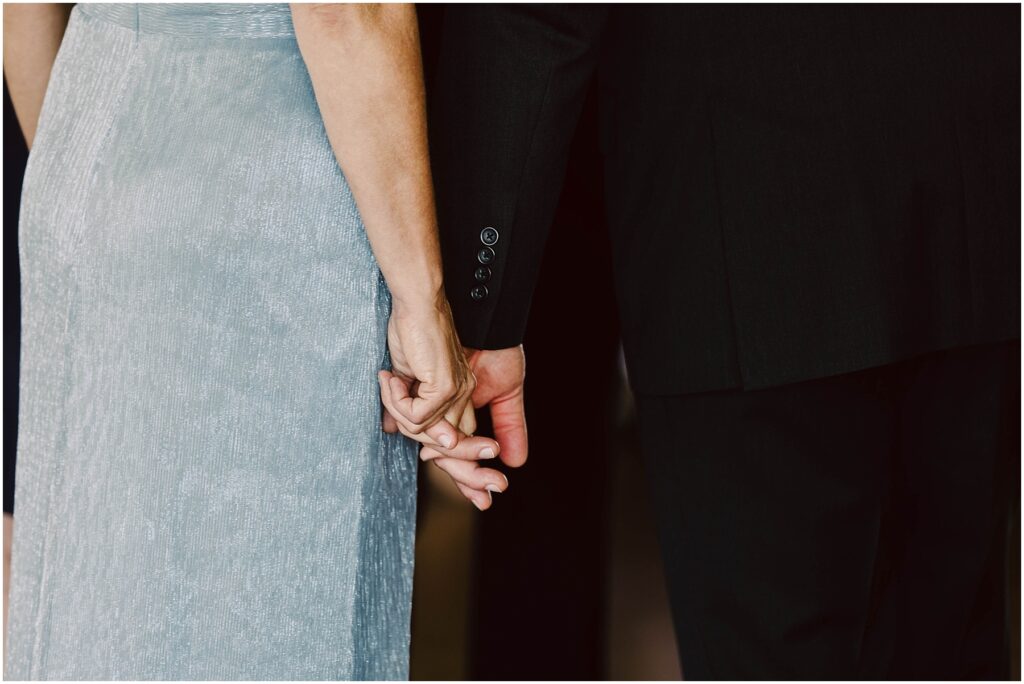 Snohomish Wedding Photographer GSquared Weddings A woman in a light blue textured dress and a man in a black suit are holding hands, with the focus on their entwined fingers. The image captures an intimate and supportive moment between the two. Serving Seattle, Snohomish and Orlando