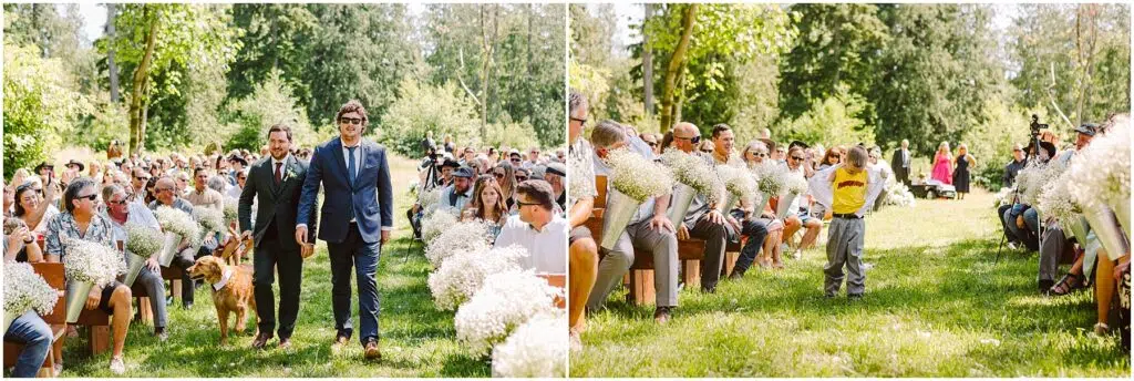 Snohomish Wedding Photographer GSquared Weddings Groomsmen in suits, one with a dog, walk down an outdoor aisle lined with guests holding white flowers. A child in a yellow shirt follows, with trees and greenery in the background under a clear sky. Serving Seattle, Snohomish and Orlando