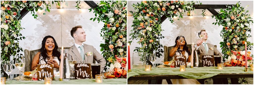 Snohomish Wedding Photographer GSquared Weddings A happy couple sits at a decorated wedding table adorned with candles and flowers. The woman laughs joyfully while the man sits beside her, in front of a greenery arch with orange and pink flowers. Signs reading Mr. are placed on the table. Serving Seattle, Snohomish and Orlando