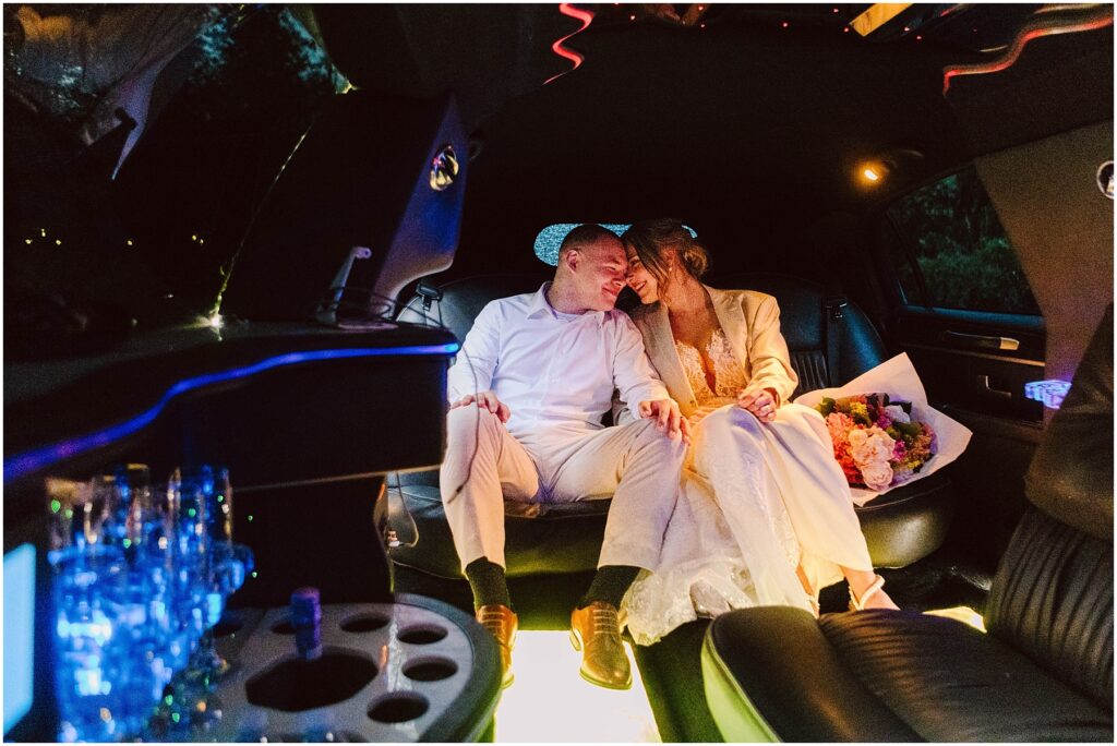 Snohomish Wedding Photographer GSquared Weddings A couple in wedding attire sits closely together inside a decorated limo. The bride holds a bouquet, and soft interior lighting creates a romantic ambiance. Glassware and decorative lights are visible around them. Serving Seattle, Snohomish and Orlando