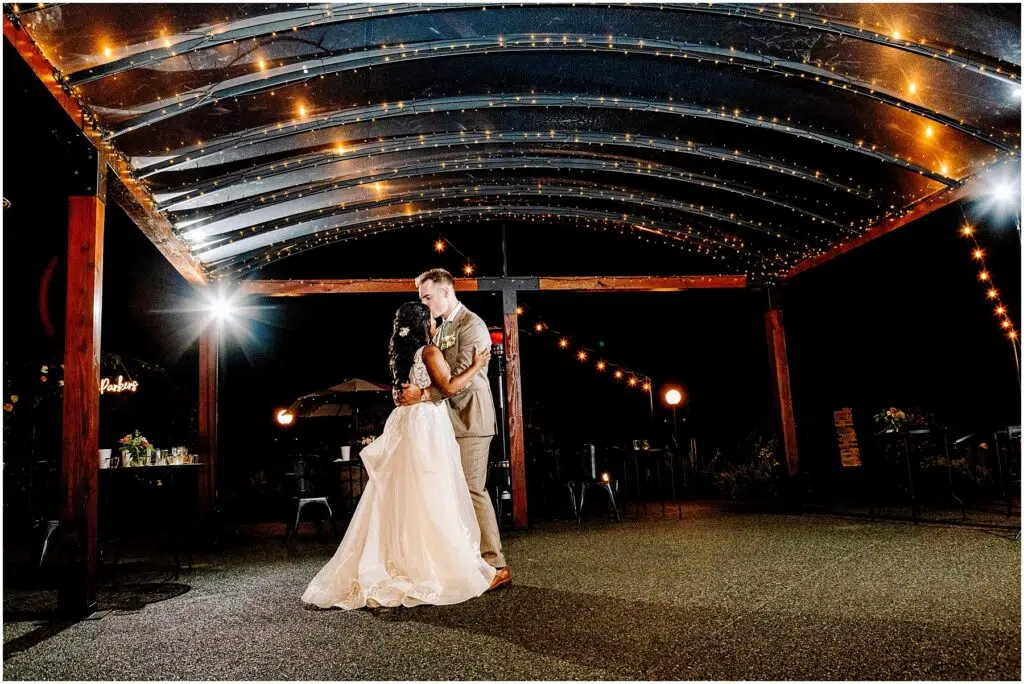 Snohomish Wedding Photographer GSquared Weddings A bride and groom share their first dance under a canopy adorned with string lights at night. The bride wears a flowing white dress, and the groom is in a light gray suit. The setting is romantic, with a dimly lit, intimate atmosphere. Serving Seattle, Snohomish and Orlando