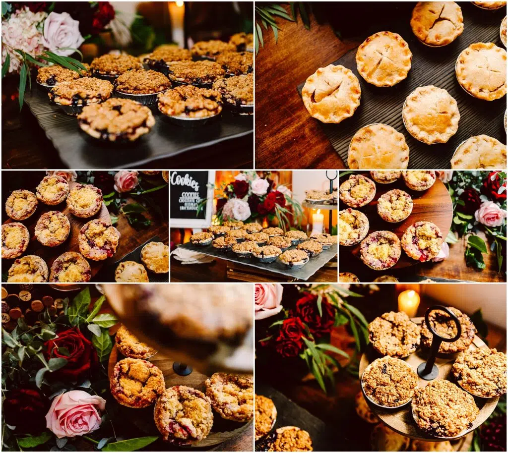 Snohomish Wedding Photographer GSquared Weddings An assortment of small pies and crumbles on display. Some are on dark trays, while others are arranged on tiered stands surrounded by decorative greenery and roses. A small blackboard sign reading Cookies is visible. The scene is warm and inviting. Serving Seattle, Snohomish and Orlando