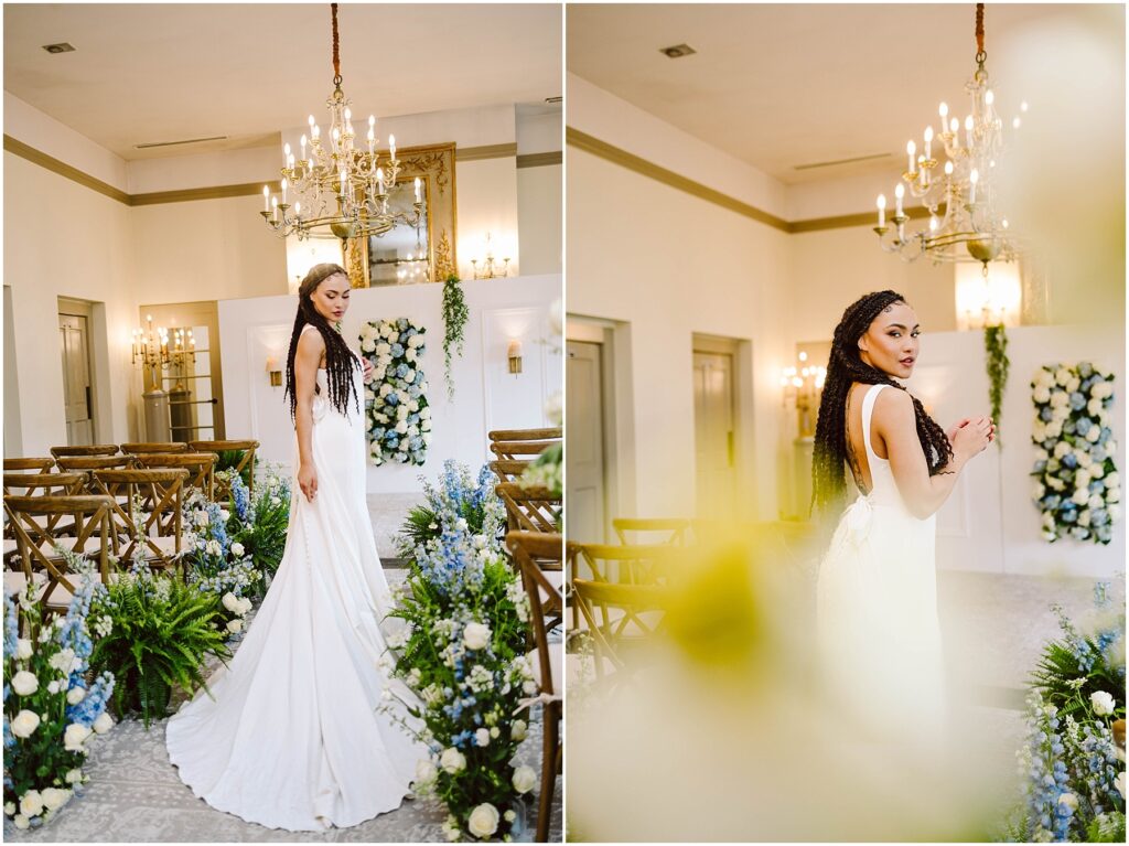 Snohomish Wedding Photographer GSquared Weddings A bride in a white gown stands in a decorated venue with chandeliers, wooden chairs, and floral arrangements featuring blue and white flowers. Her hair is styled in long braids. The setting is elegant and romantic. Serving Seattle, Snohomish and Orlando