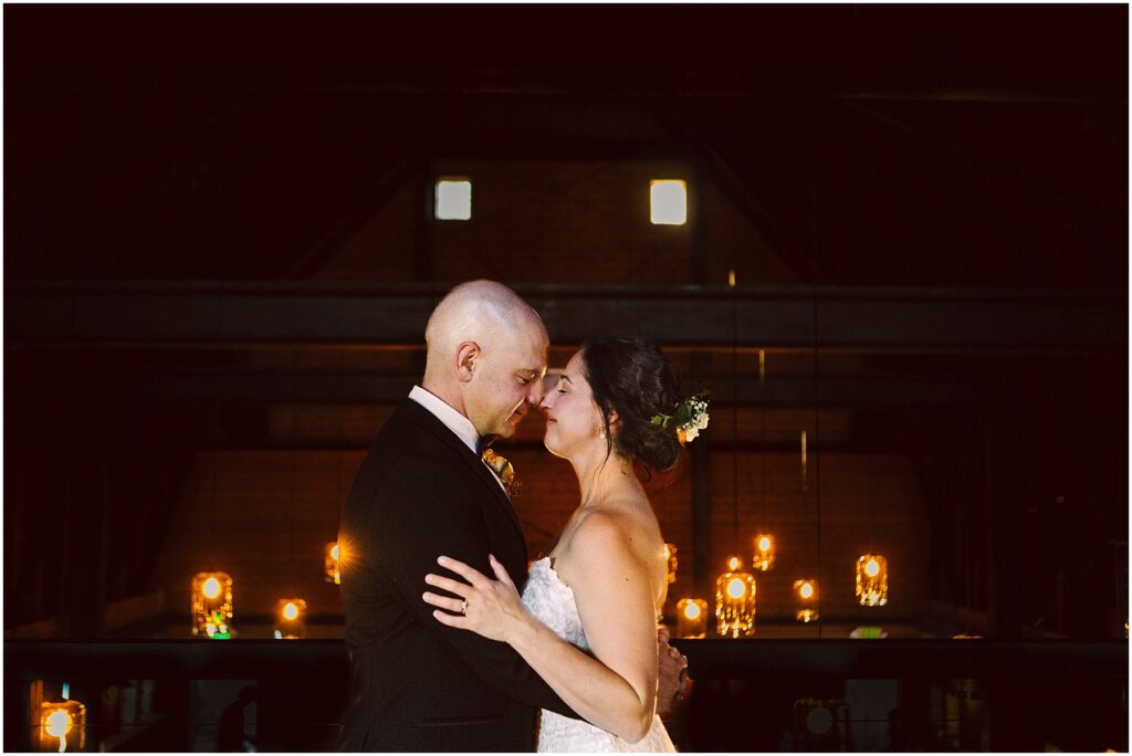 Snohomish Wedding Photographer GSquared Weddings A couple in formal attire shares a tender moment, gently touching foreheads. The dimly lit background features a row of glowing lights and candles, creating a romantic atmosphere. Serving Seattle, Snohomish and Orlando