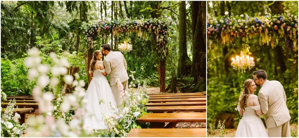 Snohomish Wedding Photographer GSquared Weddings A couple embraces under a floral arbor in a forest setting. The bride wears a white gown, while the groom is in a light suit. Wooden benches line the path, and a chandelier hangs above them, adding a touch of elegance to the natural surroundings. Serving Seattle, Snohomish and Orlando