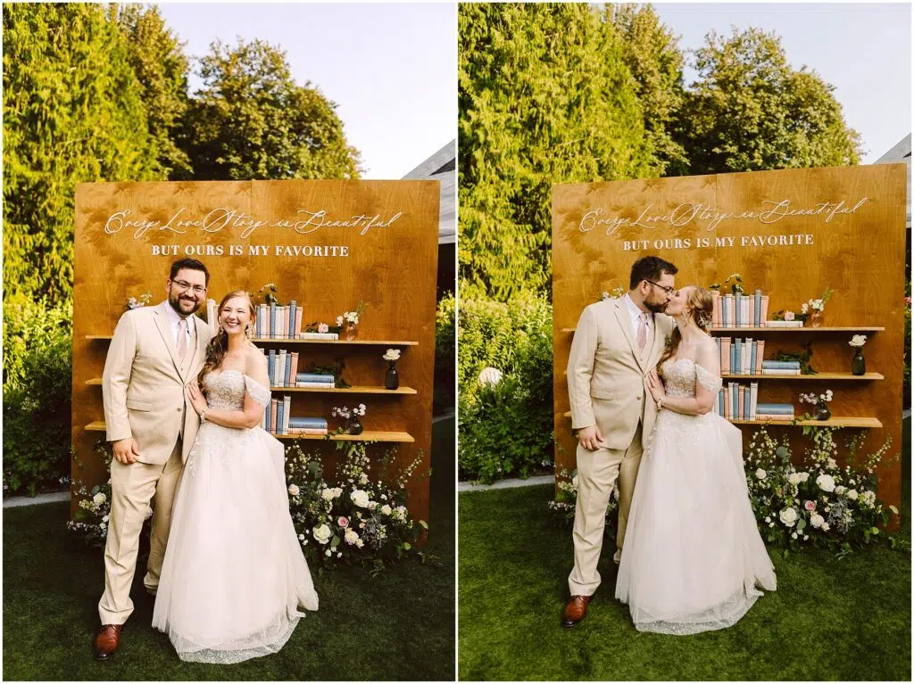 Snohomish Wedding Photographer GSquared Weddings A bride in a white gown and groom in a beige suit pose joyfully in front of a wooden backdrop with shelves and books. The backdrop reads, Every Love Story is Beautiful, But Ours is My Favorite. Greenery and flowers decorate the scene. Serving Seattle, Snohomish and Orlando