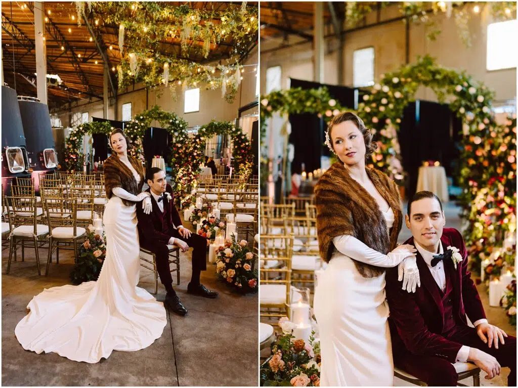 Snohomish Wedding Photographer GSquared Weddings A bride in a white gown and fur stole stands beside a seated groom in a burgundy suit. They are in a decorated indoor venue with flower arrangements and chandelier lights. The setting appears elegant and romantic. Serving Seattle, Snohomish and Orlando