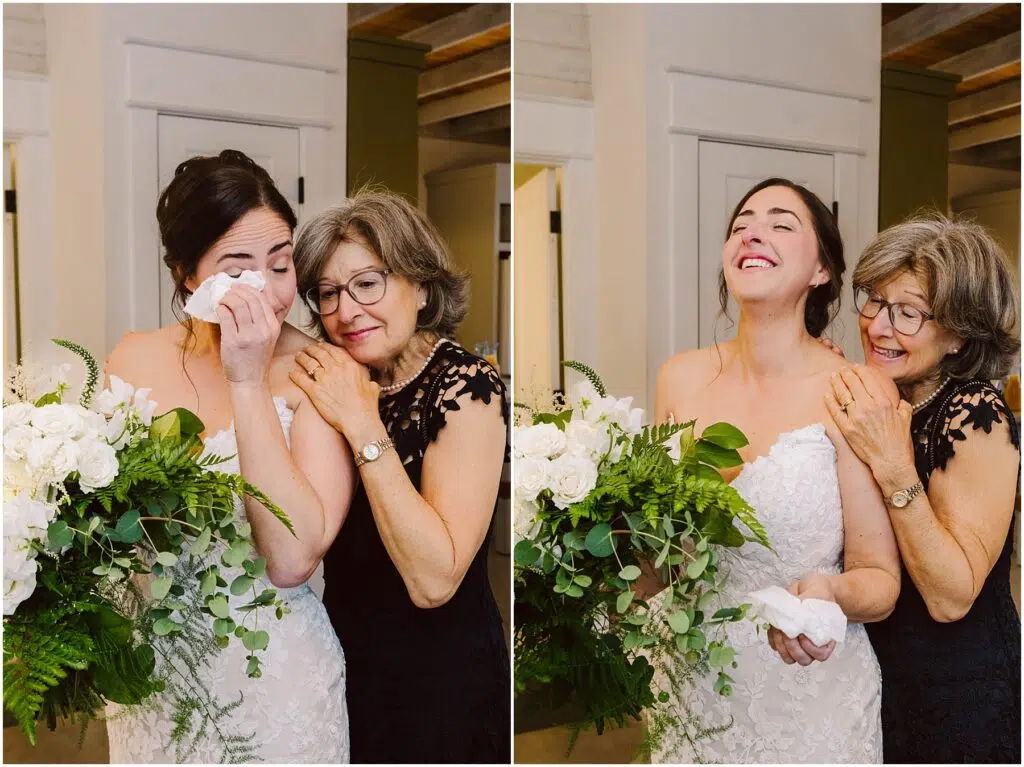 Snohomish Wedding Photographer GSquared Weddings A bride in a white dress holds a bouquet of white flowers and ferns, wiping tears with a tissue. An older woman in a black dress, beside her, smiles and comforts her. They both appear joyful in a bright indoor setting. Serving Seattle, Snohomish and Orlando