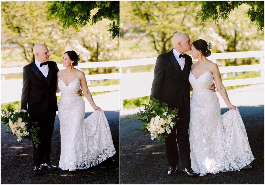 Snohomish Wedding Photographer GSquared Weddings A bride and groom walk arm in arm on a sunlit path against a white fence. The bride wears a lacy white gown and holds a bouquet of white flowers. The groom is in a black suit. They share joyful expressions and a kiss. Trees provide a lush background. Serving Seattle, Snohomish and Orlando