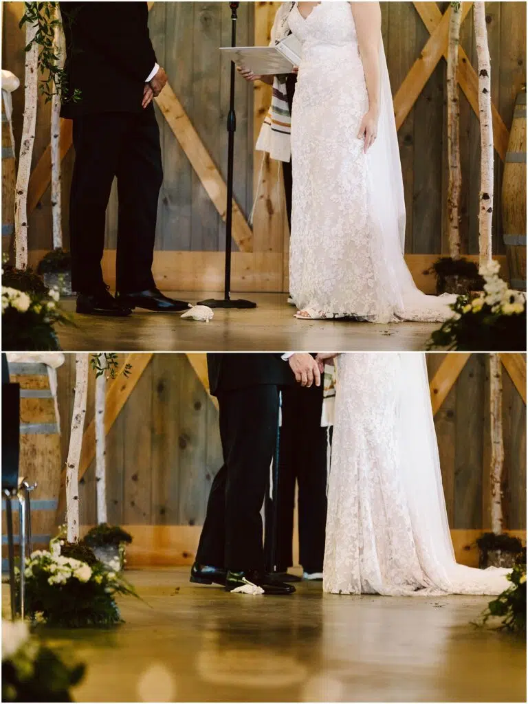 Snohomish Wedding Photographer GSquared Weddings A bride and groom stand under a rustic canopy during their wedding ceremony. The bride wears a lace gown, and the groom is in a black suit. White flowers and greenery decorate the wooden setting. A glass is seen on the floor, possibly for a traditional ritual. Serving Seattle, Snohomish and Orlando