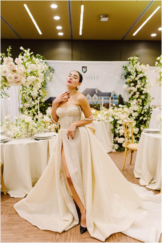 Snohomish Wedding Photographer GSquared Weddings Woman in a glamorous strapless gown poses confidently in an elegant setting adorned with white flowers and greenery. She holds a playful expression with eyes closed, and the atmosphere is sophisticated and luxurious. Serving Seattle, Snohomish and Orlando