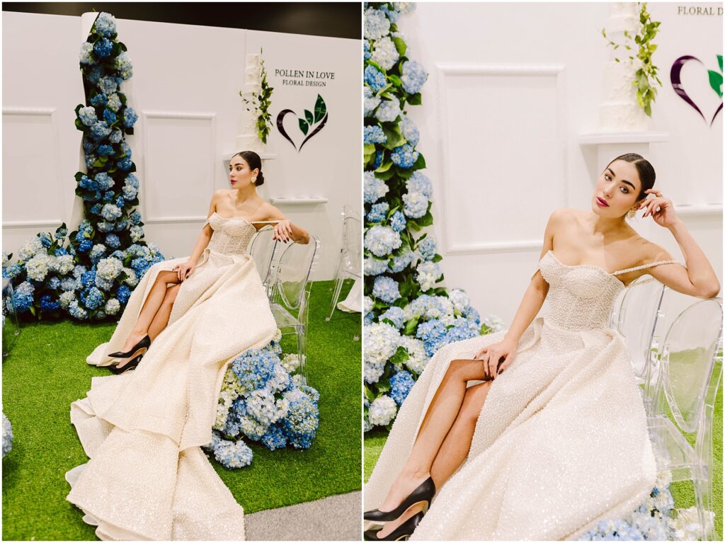 Snohomish Wedding Photographer GSquared Weddings A woman in an elegant, off-shoulder gown sits on a clear chair surrounded by blue hydrangeas. The setting includes green artificial grass and a white backdrop with Pollen in Love Floral Design displayed. Serving Seattle, Snohomish and Orlando