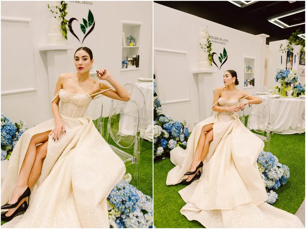 Snohomish Wedding Photographer GSquared Weddings A woman in an elegant cream gown with high slits poses gracefully on a transparent chair. The setting features white walls with floral arrangements and blue hydrangeas, creating a sophisticated ambiance. Serving Seattle, Snohomish and Orlando