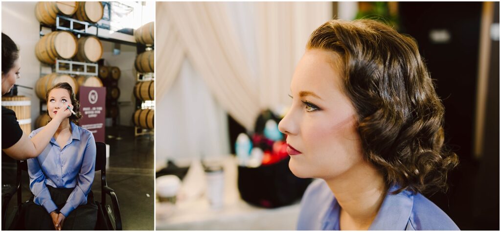 Snohomish Wedding Photographer GSquared Weddings A woman in a blue shirt getting makeup applied by another person. Shes seated indoors, with a background of stacked barrels and a blurred interior setting. Close-up on her face shows elegant makeup and styled hair. Serving Seattle, Snohomish and Orlando