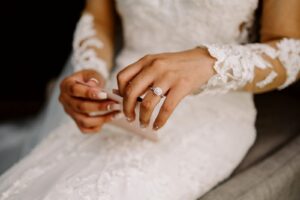Snohomish Wedding Photographer GSquared Weddings A bride in an intricately detailed lace wedding dress and sheer sleeves holds a folded piece of paper. Her left hand, adorned with a diamond ring, is central in the image, showcasing her elegant manicure. Serving Seattle, Snohomish and Orlando