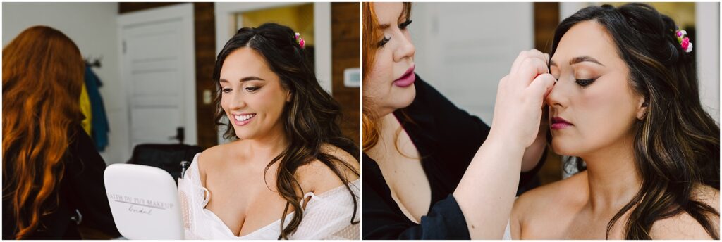 Snohomish Wedding Photographer GSquared Weddings In a room with white walls and wooden accents, a woman with long dark hair smiles as she holds a mirror. Nearby, another person with red hair carefully applies makeup to her face, creating a serene moment reminiscent of a tranquil morning in Machias. Serving Seattle, Snohomish and Orlando