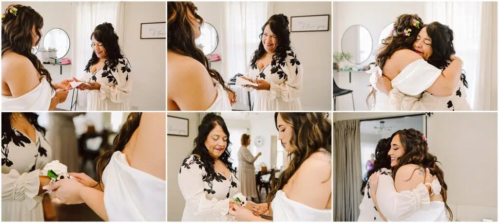 Snohomish Wedding Photographer GSquared Weddings In a sunlit room in Machias, a bride adorned with a floral crown and an off-shoulder dress shares a heartfelt moment with another woman. They exchange gifts, smile warmly, and embrace as their reflections dance in the mirror beside the soft curtains. Serving Seattle, Snohomish and Orlando