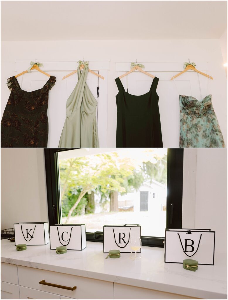 Snohomish Wedding Photographer GSquared Weddings Four dresses hang on a wall: a dark patterned one, a light green, a black, and floral—perfect for a summer wedding in Port Gamble. Below, four black-edged placards with the letters K, C, R, and B adorn the countertop with small green candles beside each. Serving Seattle, Snohomish and Orlando