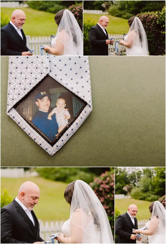 Snohomish Wedding Photographer GSquared Weddings At a charming Port Gamble summer wedding, a bride and groom exchange vows outdoors. The bride clutches a handkerchief while the groom holds a box. A tie featuring a photo of an adult and baby is displayed as they stand by a white fence and garden, framed by lush trees. Serving Seattle, Snohomish and Orlando
