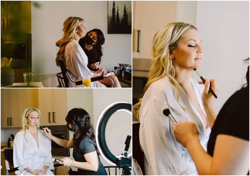 Snohomish Wedding Photographer GSquared Weddings A woman with long blonde hair in a white robe is having her makeup done by a stylist, reminiscent of the meticulous care taken at a winery. The stylist expertly applies makeup with brushes, framed by the glow of a ring light and an array of makeup products. Serving Seattle, Snohomish and Orlando