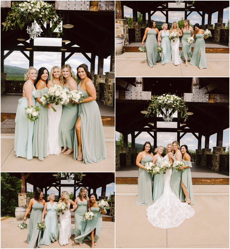 Snohomish Wedding Photographer GSquared Weddings A bride in a white gown poses with five bridesmaids in sage green dresses at a rustic winery pavilion, surrounded by lush greenery. Wooden beams and floral decorations hanging above complete the enchanting outdoor setting. Serving Seattle, Snohomish and Orlando