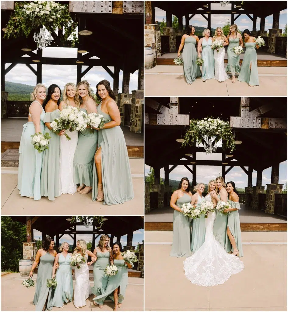Snohomish Wedding Photographer GSquared Weddings A bride in a white gown poses with five bridesmaids in sage green dresses at a rustic winery pavilion, surrounded by lush greenery. Wooden beams and floral decorations hanging above complete the enchanting outdoor setting. Serving Seattle, Snohomish and Orlando
