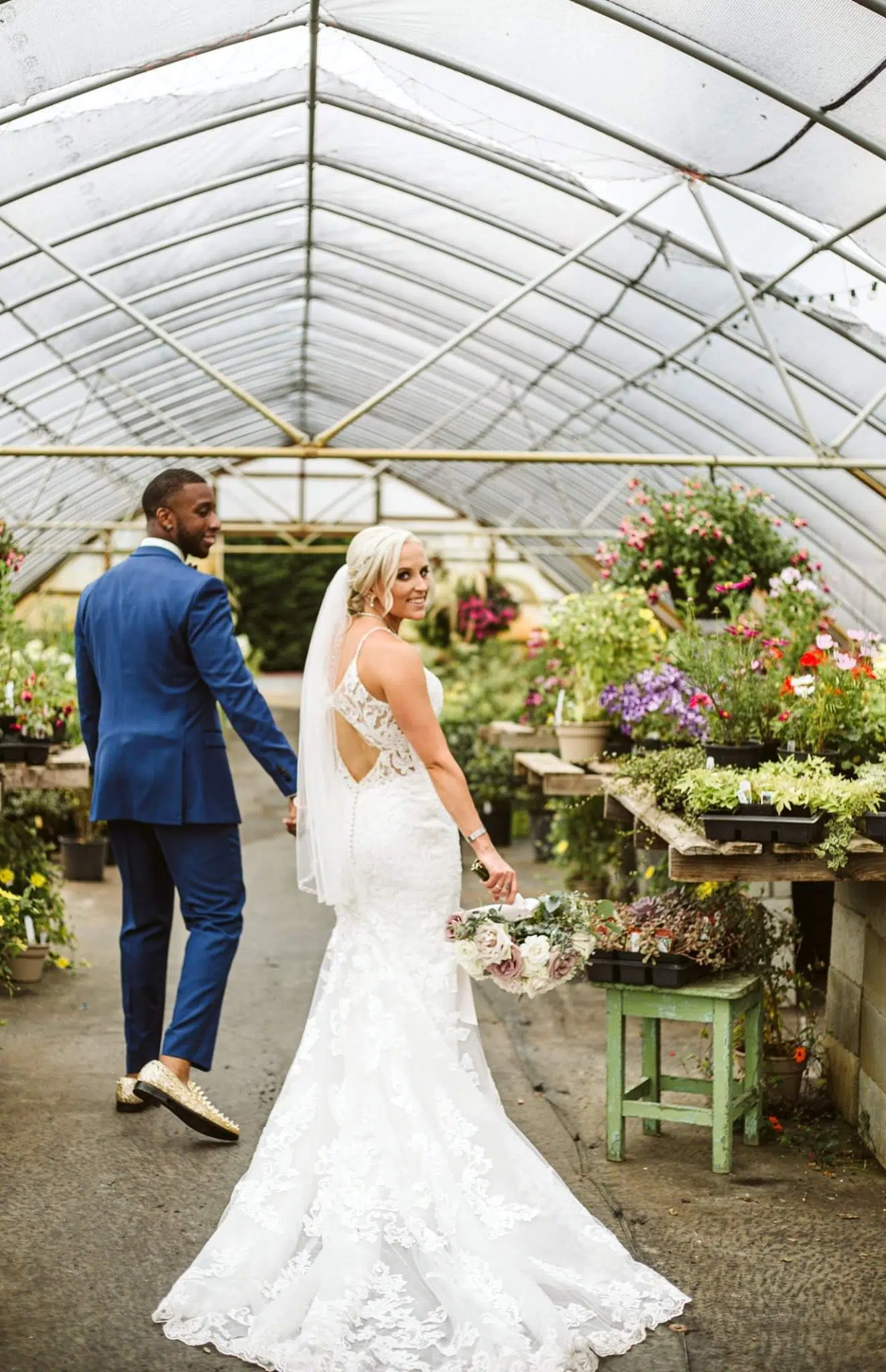 Snohomish Wedding Photographer GSquared Weddings A bride in a white lace gown and veil holds a bouquet while walking handinhand with a groom in a blue suit through a greenhouse filled with colorful flowers both smiling back toward the camera Serving Seattle Snohomish and Orlando Snohomish Wedding Photographer GSquared Weddings A bride in a white lace gown and veil holds a bouquet while walking hand in hand with a groom in a blue suit through a greenhouse filled with colorful flowers both smiling back toward the camera Serving Seattle Snohomish and Orlando