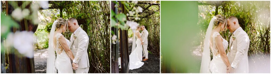 Snohomish Wedding Photographer GSquared Weddings A bride and groom stand close under a leafy pergola in Snohomish, holding hands and touching foreheads. The bride wears a white gown with lace details, and the groom is in a light beige suit. The scene is serene and intimate, surrounded by lush greenery. Serving Seattle, Snohomish and Orlando