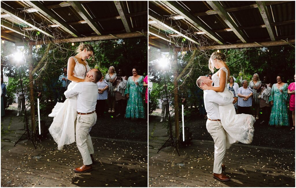 Snohomish Wedding Photographer GSquared Weddings A groom lifts the bride joyfully under a wooden pergola in Snohomish. Guests stand in the background, smiling. The bride wears a white gown, and the groom is in light-colored attire. The scene is festive with string lights and scattered petals. Serving Seattle, Snohomish and Orlando