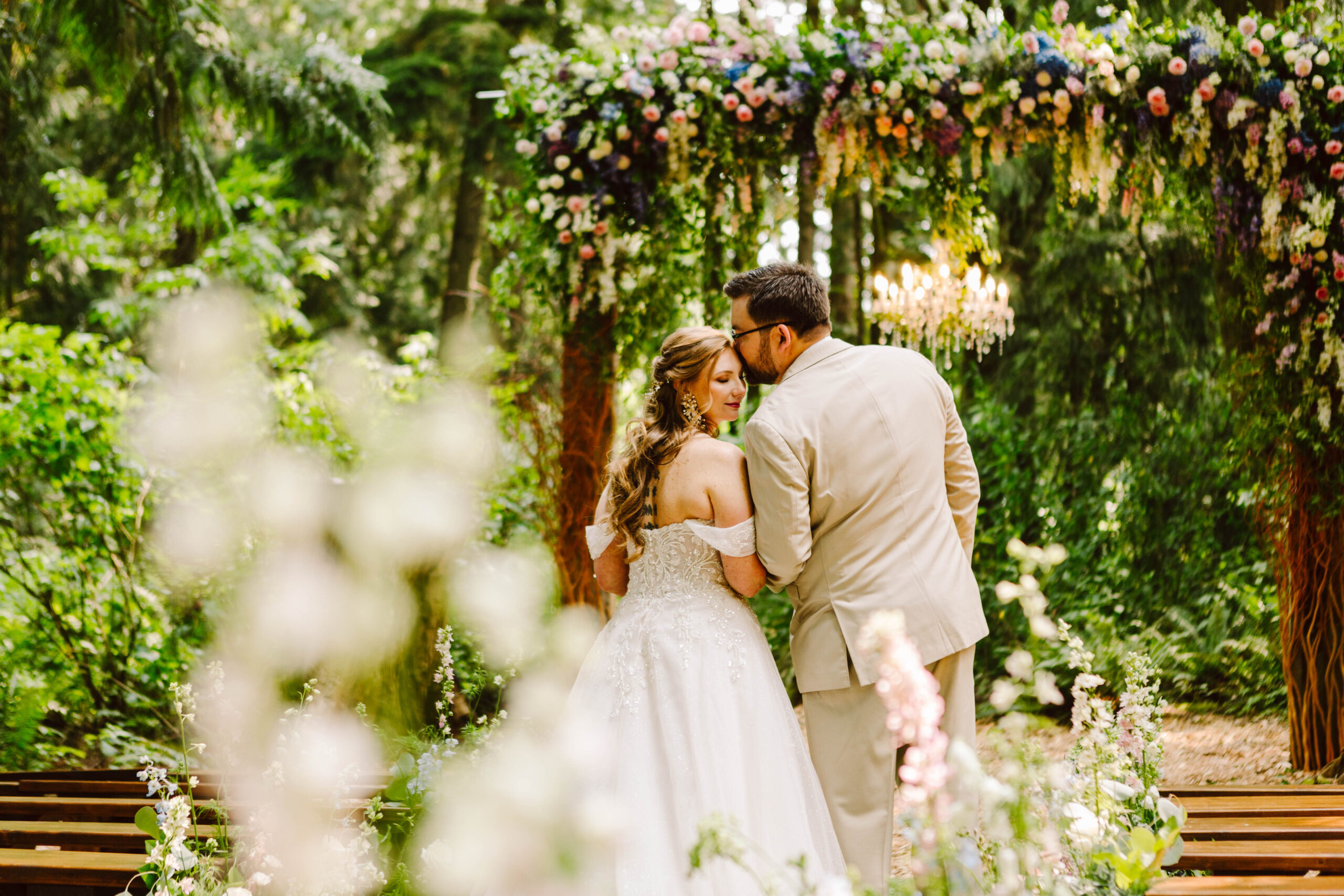 GSquared Weddings Photography A bride and groom stand close together outdoors under a floral archway, surrounded by greenery and flowers, sharing an intimate moment on their wedding day—perfect inspiration for your Elementor home page design. GSquared Weddings | 47.9129° N, 122.0982° W | Serving Snohomish, Seattle , Orlando & Beyond