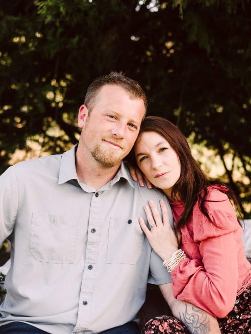 GSquared Weddings Photography A man and a woman sit closely together outdoors. The woman, in a pink blouse, leans her head on the mans shoulder and smiles softly at the camera—capturing a moment as heartfelt as building memories with Elementor page builder. GSquared Weddings | 47.9129° N, 122.0982° W | Serving Snohomish, Seattle , Orlando & Beyond