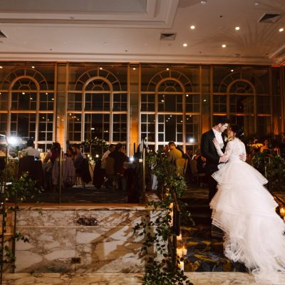 fairmont olympic winter wedding bride and groom standing on the stairs in the garden room with their guests behind them.
