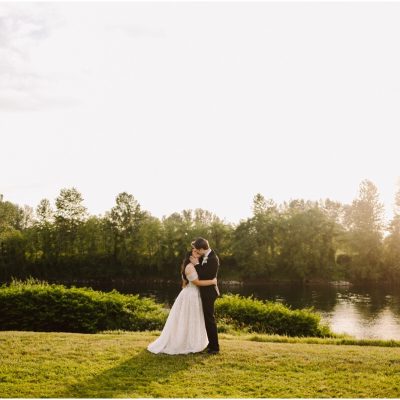 classic wedding at pemberton farm in snohomish bride and groom kissing on the grass with river in the background